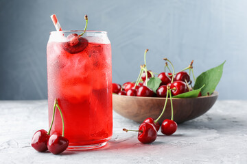 Tasty cherry soda with ice cubes and berries on grey textured table, closeup