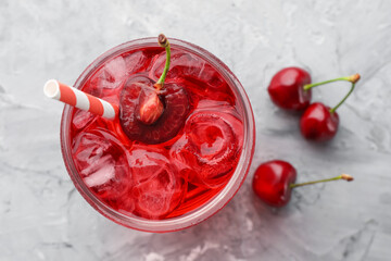 Tasty cherry soda with ice cubes and berries on grey textured table, flat lay