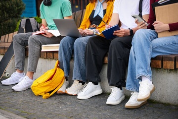Teenagers studying together on bench outdoors, closeup