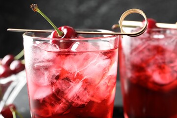 Tasty cherry soda with ice cubes and berries in glasses on table, closeup