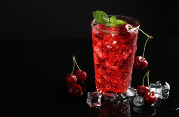 Tasty cherry soda with ice cubes, berries and mint in glass on black background, closeup. Space for...