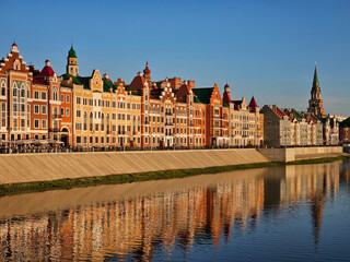 Naklejka premium City with a river running through it. The buildings are tall and colorful. The water is calm and reflects the buildings in Yoshkar-Ola - capital of the Republic of Mari El in Russia