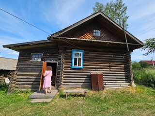 Girl woman in a pink dress is walking up the steps to a house. The house is old and has a wooden...
