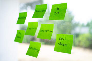 Teamwork, innovation and strategy: sticky notes on glass for next steps and to do list