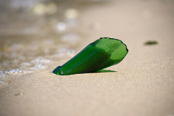 Green Glass Bottle Shard on Sandy Beach, Environmental Pollution Concept