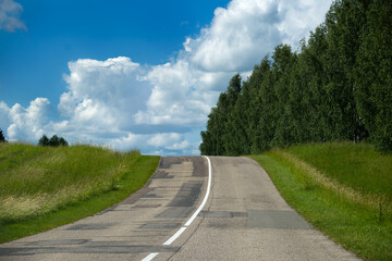 The road climbs towards a bright, cloudy sky, inviting travel and adventure.