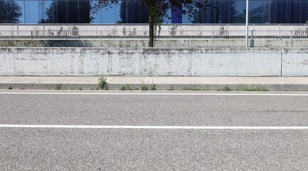 Concrete white fence with railings and a modern glass facade on behind. Sidewalk and street in front. background for copy space.