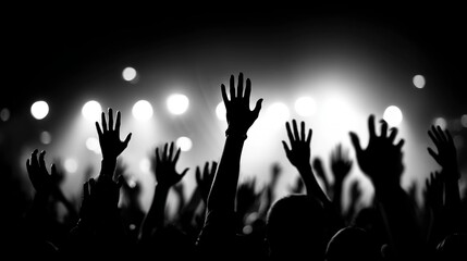 Silhouetted hands raised by a crowd at a concert with bright lights