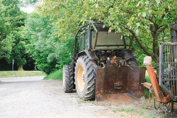 Parked tractor on dry dirt patch surrounded by summer warmth. Concept: farm life, machinery rest,...