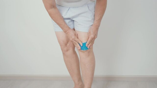 Elderly woman having knee ache with cold gel pack to Runners Knee or Patellofemoral Pain Syndrome, osteoarthritis, arthritis, rheumatism and Patellar Tendinitis. Senior health