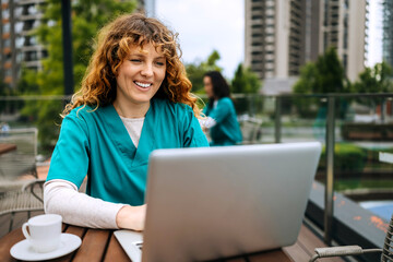 Healthcare professional working on a laptop outdoors in a city setting during the day