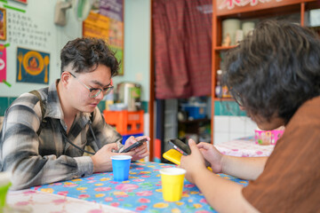 Two Chinese men in their early twenties, both wearing glasses, are casually waiting at a Thai...