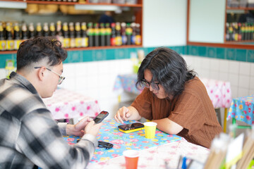Two Chinese men in their early twenties, both wearing glasses, are casually waiting at a Thai...