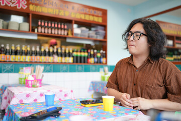 Two Chinese men in their early twenties, both wearing glasses, are casually waiting at a Thai...