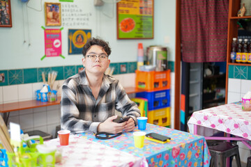 Two Chinese men in their early twenties, both wearing glasses, are casually waiting at a Thai...