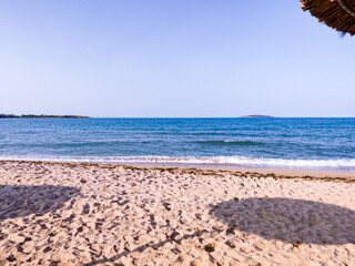 Beach, sea, empty sky and island in the distance