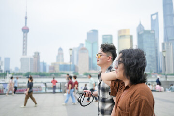 Two young Chinese men in their early twenties, both wearing glasses, walk side by side along the...