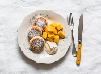 Delicious breakfast, brunch - homemade syrniki with sour cream and fresh mango on a light...