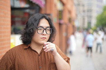 A young Chinese man in his early twenties, wearing glasses, is sitting at a modern cafe, calmly...