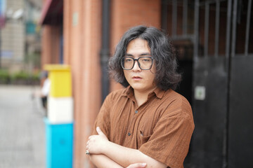 A young Chinese man in his early twenties, wearing glasses, is sitting at a modern cafe, calmly...