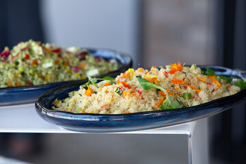 Delicious couscous salad with edible flowers and vegetables displayed on buffet table