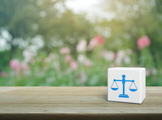 Law flat icon on white block cube on wooden table over blur pink flower and tree in garden, Business legal service concept