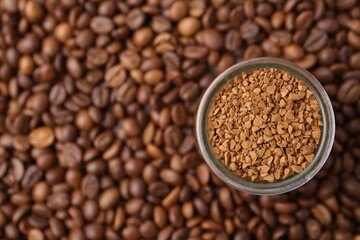 Glass jar with granulated instant coffee on beans, top view. Space for text