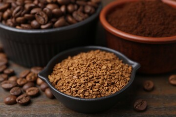 Different types of instant coffee and beans in bowls on wooden table, closeup