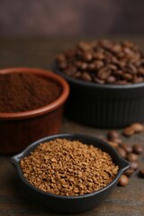 Different types of instant coffee and beans in bowls on wooden table against brown background, closeup