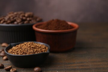 Different types of instant coffee and beans in bowls on wooden table against brown background, closeup