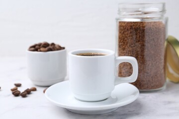 Aromatic hot drink, instant coffee and beans on white marble table, closeup