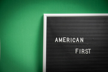 American First concept on black board with green background. Partial view of a black letter board...