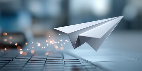 White Paper Airplane with Sparkles Flying Over Laptop Keyboard in Blurred Office Background

