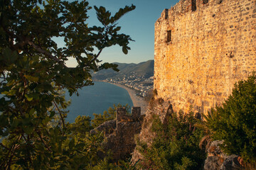 Ancient coastal fortress in Turkey with green foliage in foreground