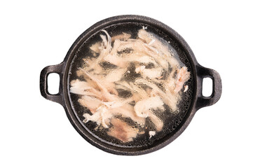 Chicken broth with meat in a skillet isolated on white background. top view