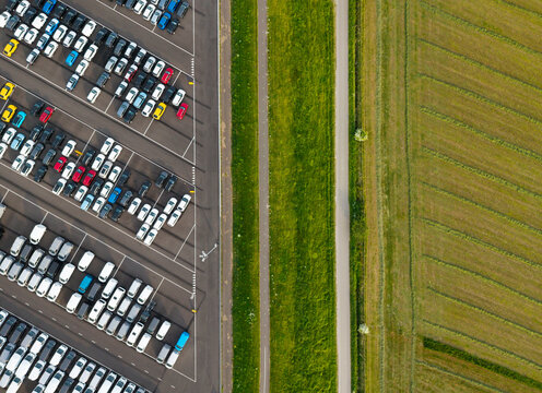 Aerial view of a parking lot with electric and petrol cars in harbour storage next to fields in the Netherlands