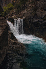 Turquoise mountain waterfall surrounded by rocks