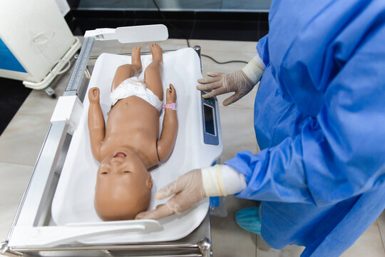 Medical student practicing with a baby doll for healthcare training in a hospital setting