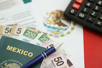 Mexican pesos money bills in big amount lies on table with pen, calculator, passport and tax forms