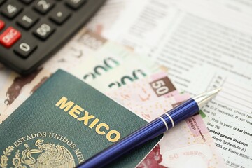 Mexican pesos money bills in big amount lies on table with pen, calculator, passport and tax forms