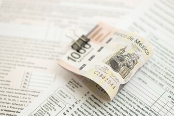 Mexican pesos money bills in big amount lies on table with tax forms close up