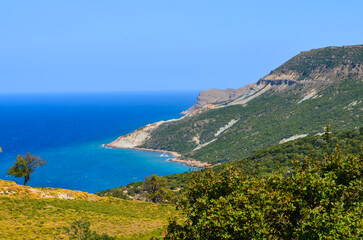 Fototapeta premium A beautiful blue ocean with a mountain in the background. The sky is clear and the sun is shining