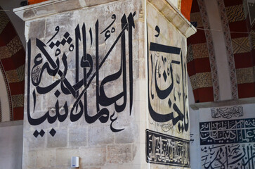 The wall is covered in Arabic writing. The writing is in black and white and is very detailed. The...