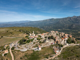 Aerial view of the medieval hilltop village of Sant’Antonino on the Mediterranean island of Corsica with mountains in the distance