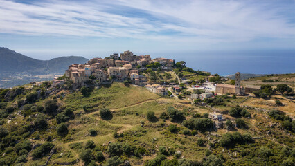 Aerial view of the medieval hilltop village of Sant’Antonino on the island of Corsica with the Meidterranean sea in the distance