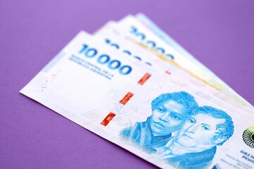 Argentine pesos money bills in big amount lies on purple color table close up