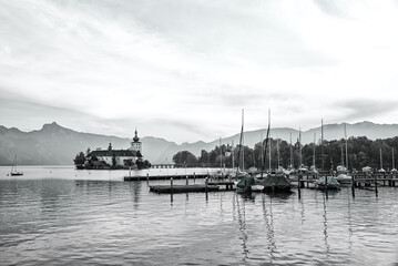 lake Traunsee with moored boats and view to Ort castle, black and white