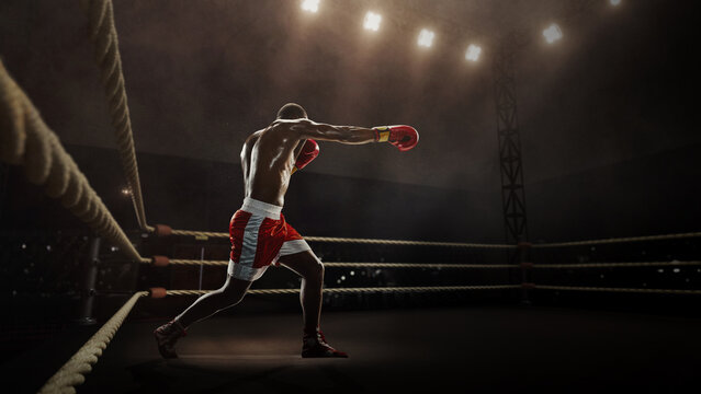 Athlete in red trunks delivers a strong punch under arena lights on a 3D boxing ring. Concept of training and performance analytics, motivational posters