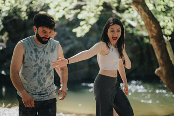 A man and woman having a joyful and carefree interaction near a beautiful forest stream, depicting...
