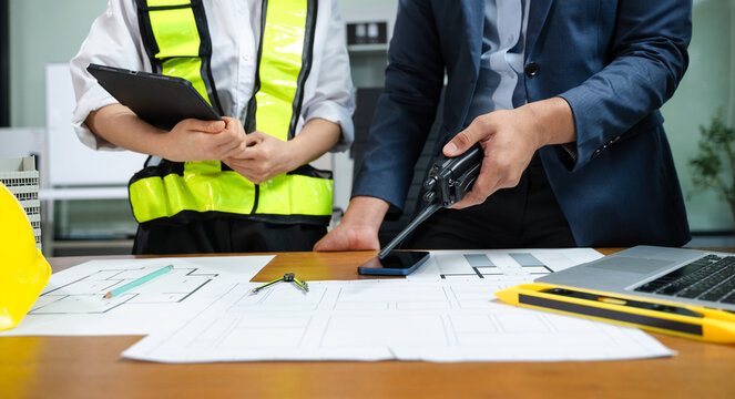 Engineer and manager reviewing construction blueprints with tablet and walkie-talkie. Teamwork, project planning